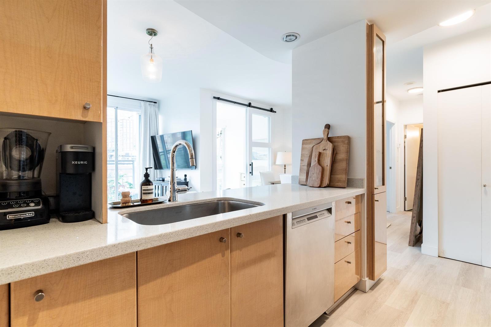 The kitchen peninsula with its sink and coffee machine, looking out to the hall.