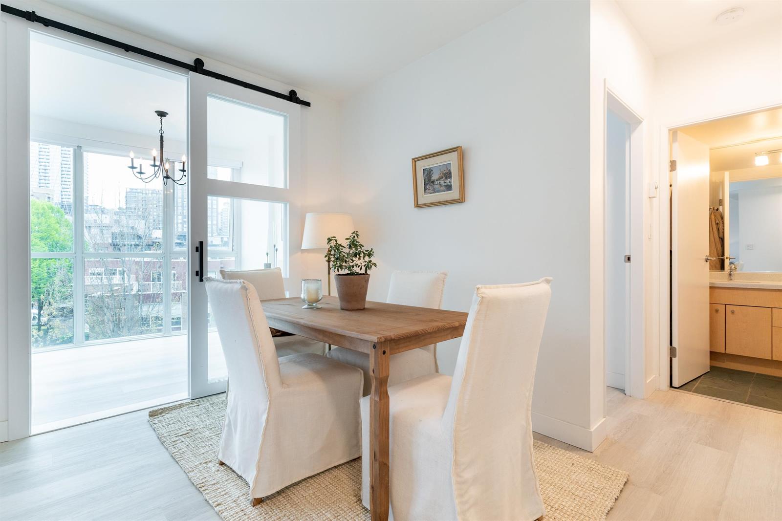 The dining table and slipcovered chairs beside the sliding door to the balcony, the barn door on its rail at the left.