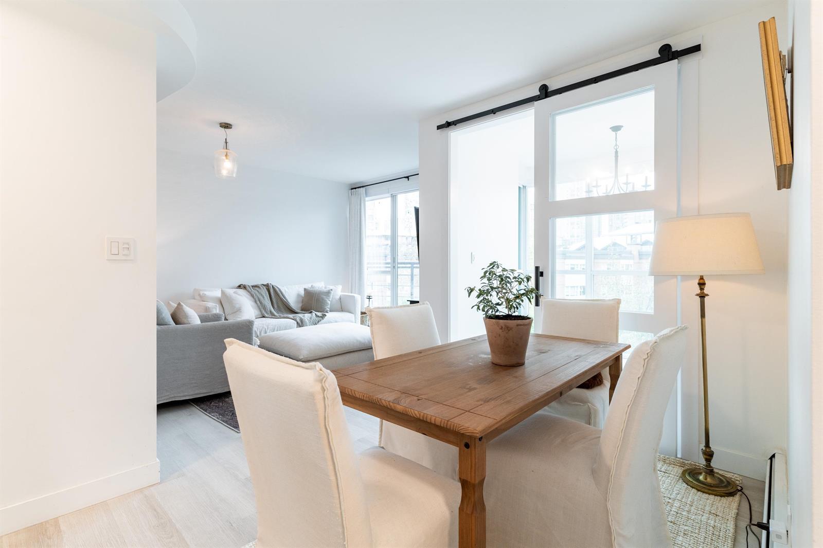 The dining table with the living room behind it, lamps either side and the sofa beyond.
