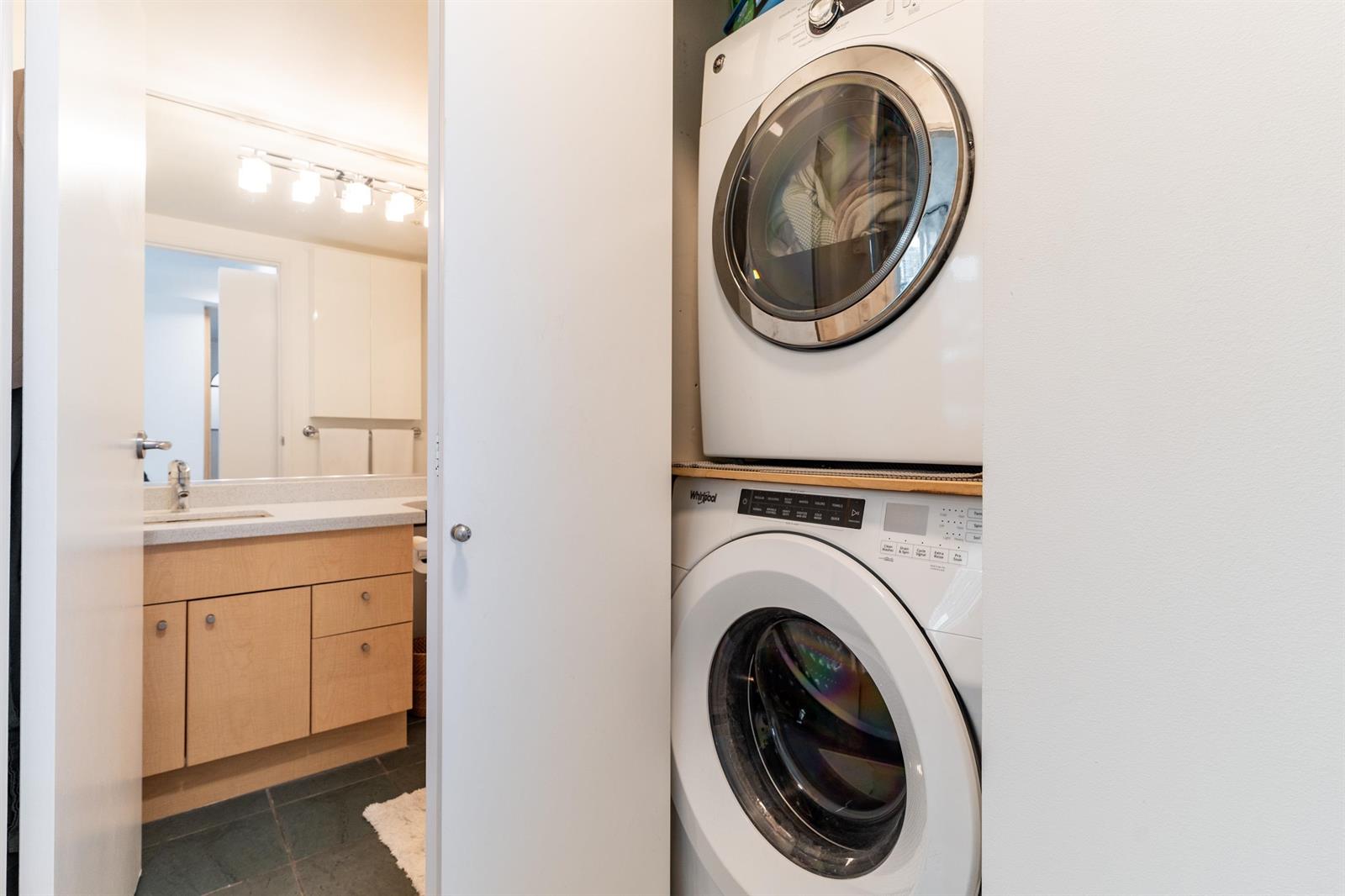 The laundry beside the vanity, a washer and dryer stacked in their alcove.