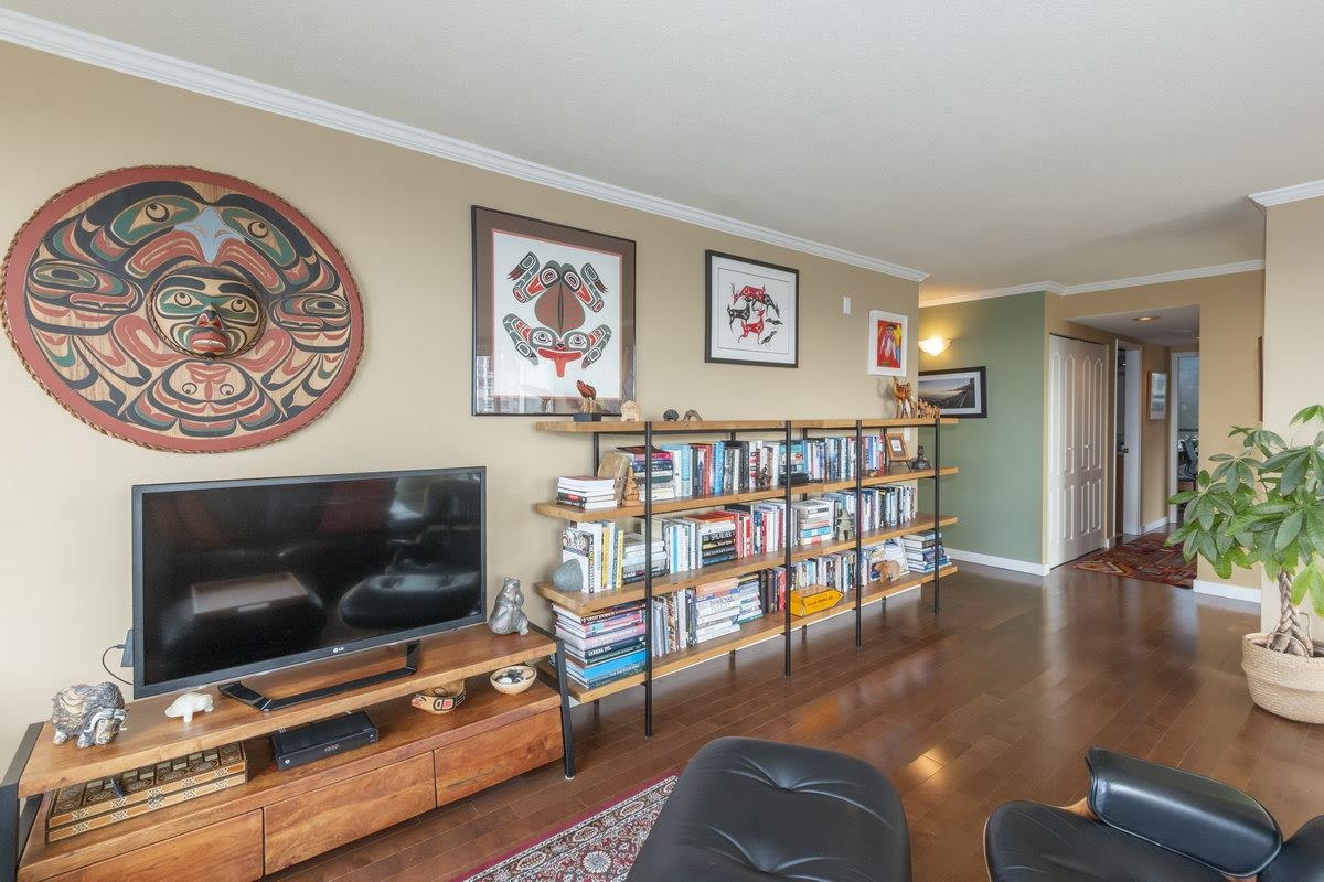 The inside wall of the living room, low shelving and books under the artwork.