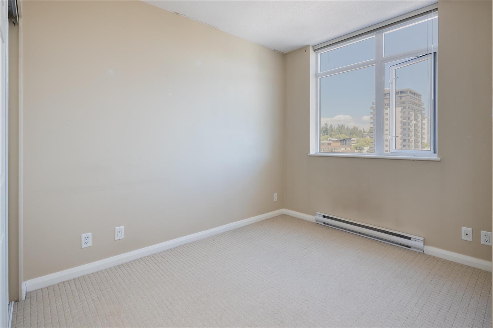 A bedroom, empty, its window looking out over the towers.