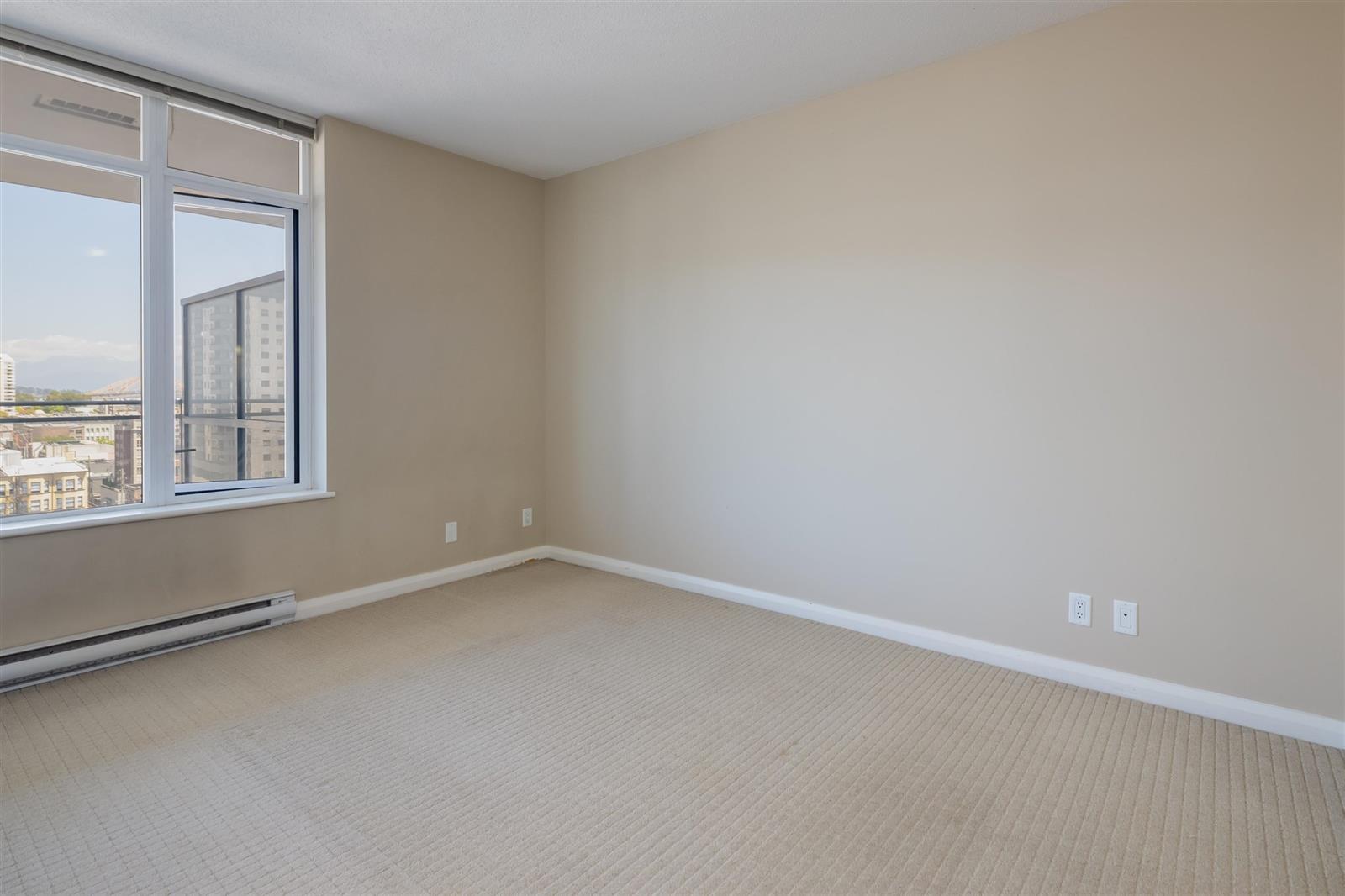 The second bedroom, a tall window along one wall with the baseboard heater beneath it.