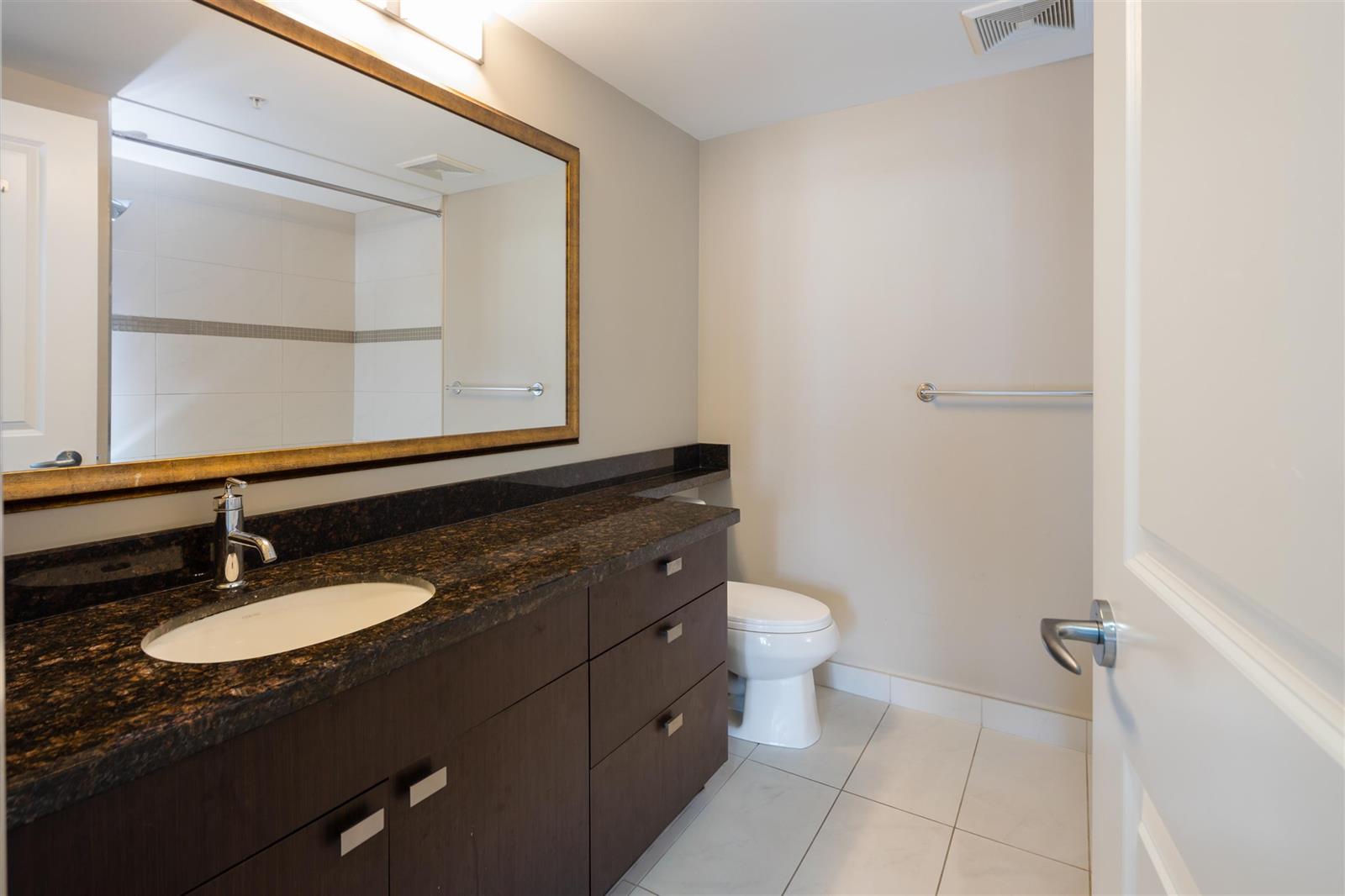 A bathroom, a granite vanity under a framed mirror.