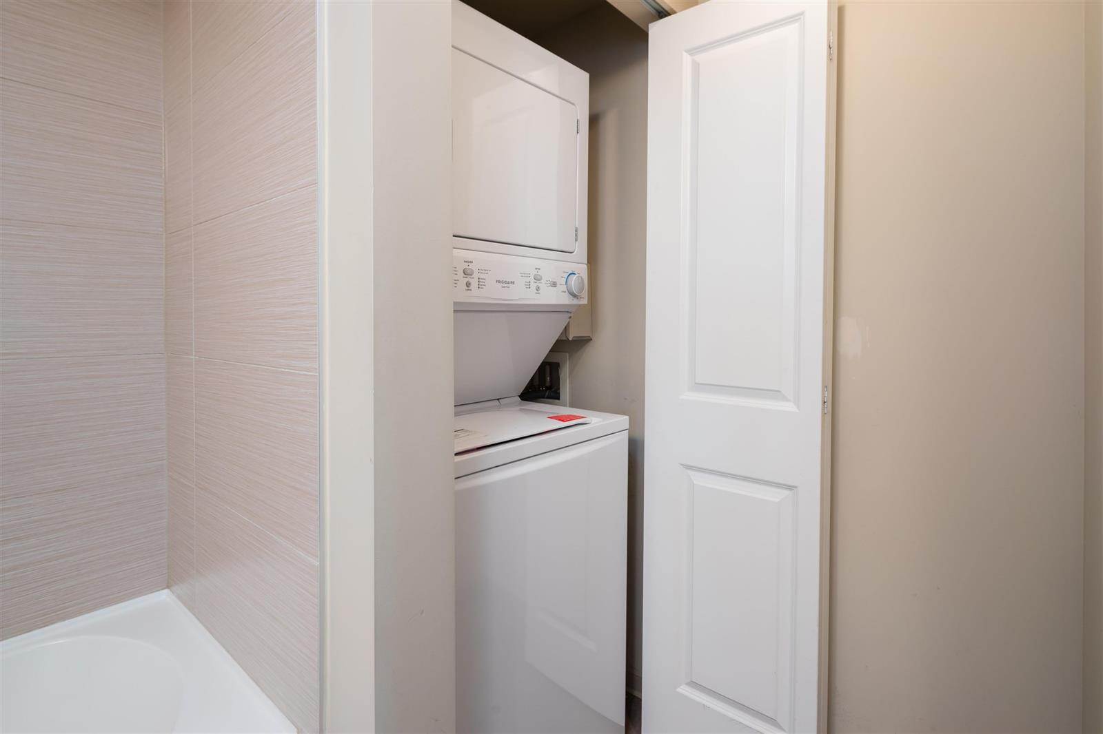 The laundry closet, a stacked washer and dryer behind folding doors.