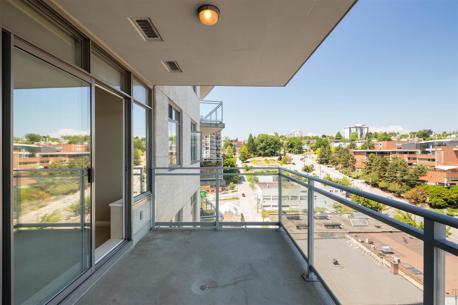 The patio from the living room door, the rail and the city stretching away.