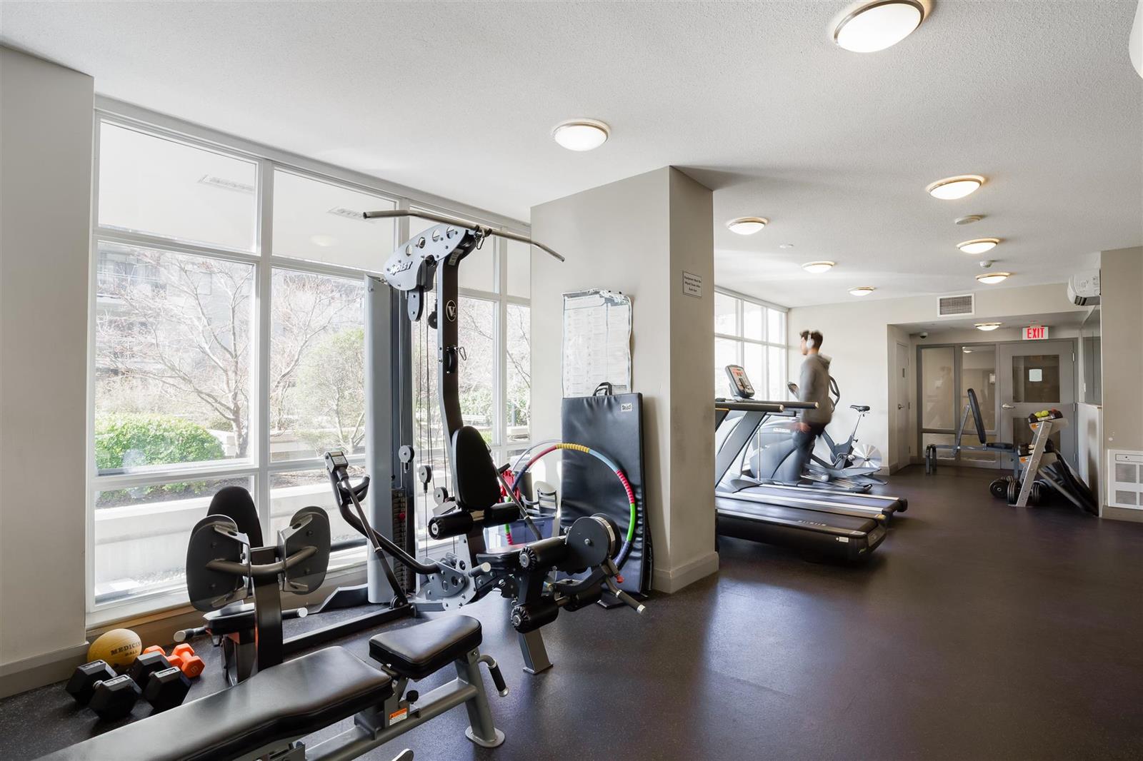The exercise room, treadmills and free weights along the windows.