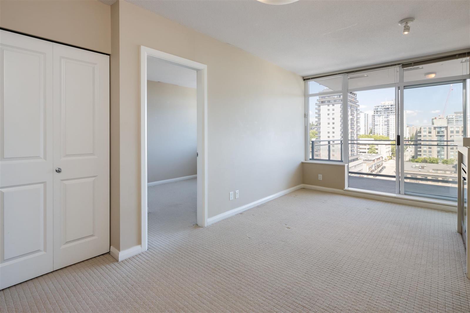 The entrance hall, closet doors on one side and the living room windows at the end of it.