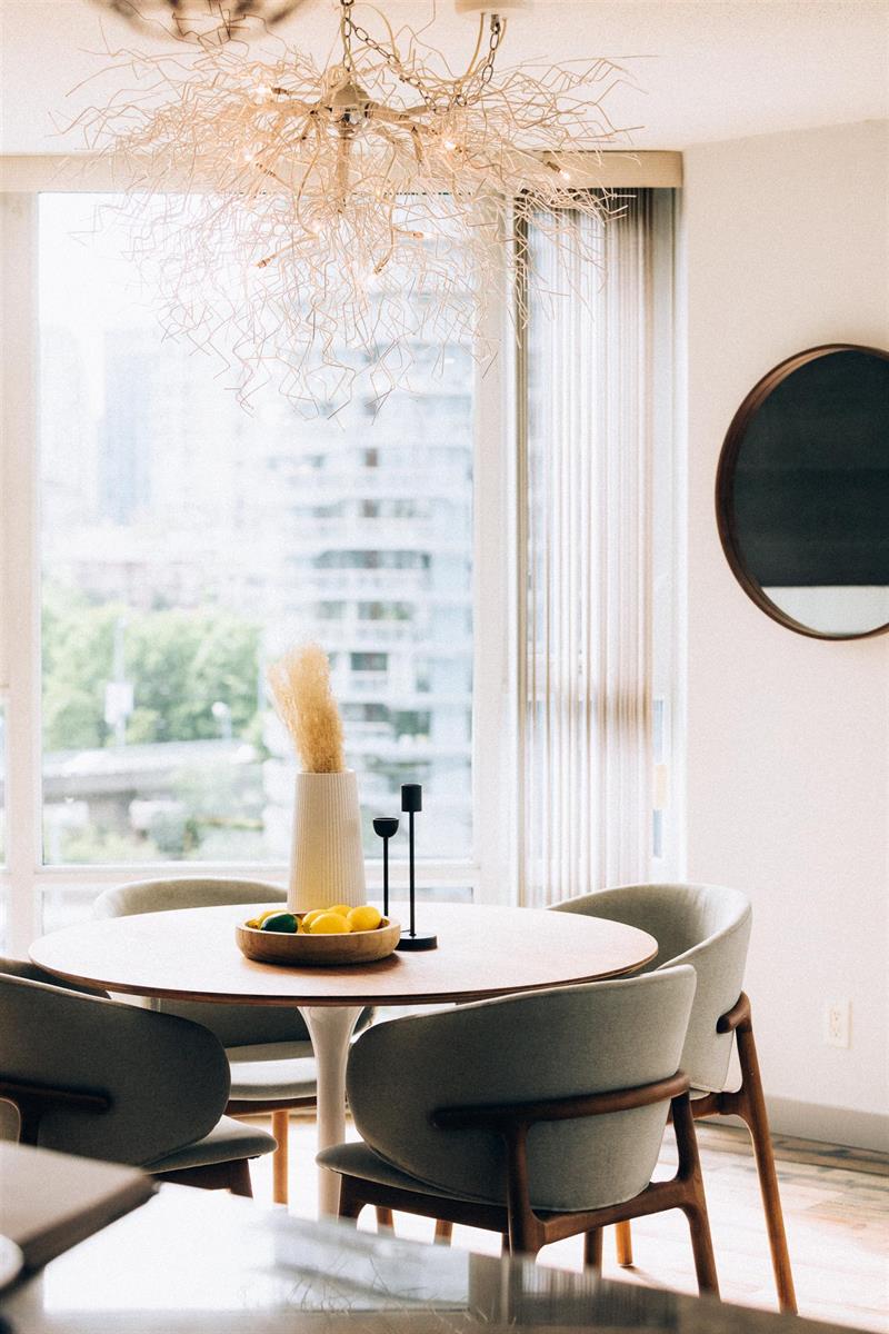 The dining table close up, the chandelier above it and the mirror on the wall beside.