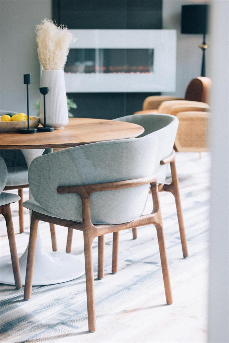 The dining chairs close up, the fireplace and a vase of grasses behind them.