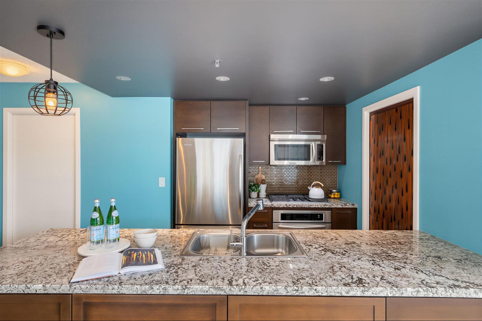 The kitchen island in granite, the fridge and the wall oven behind it.