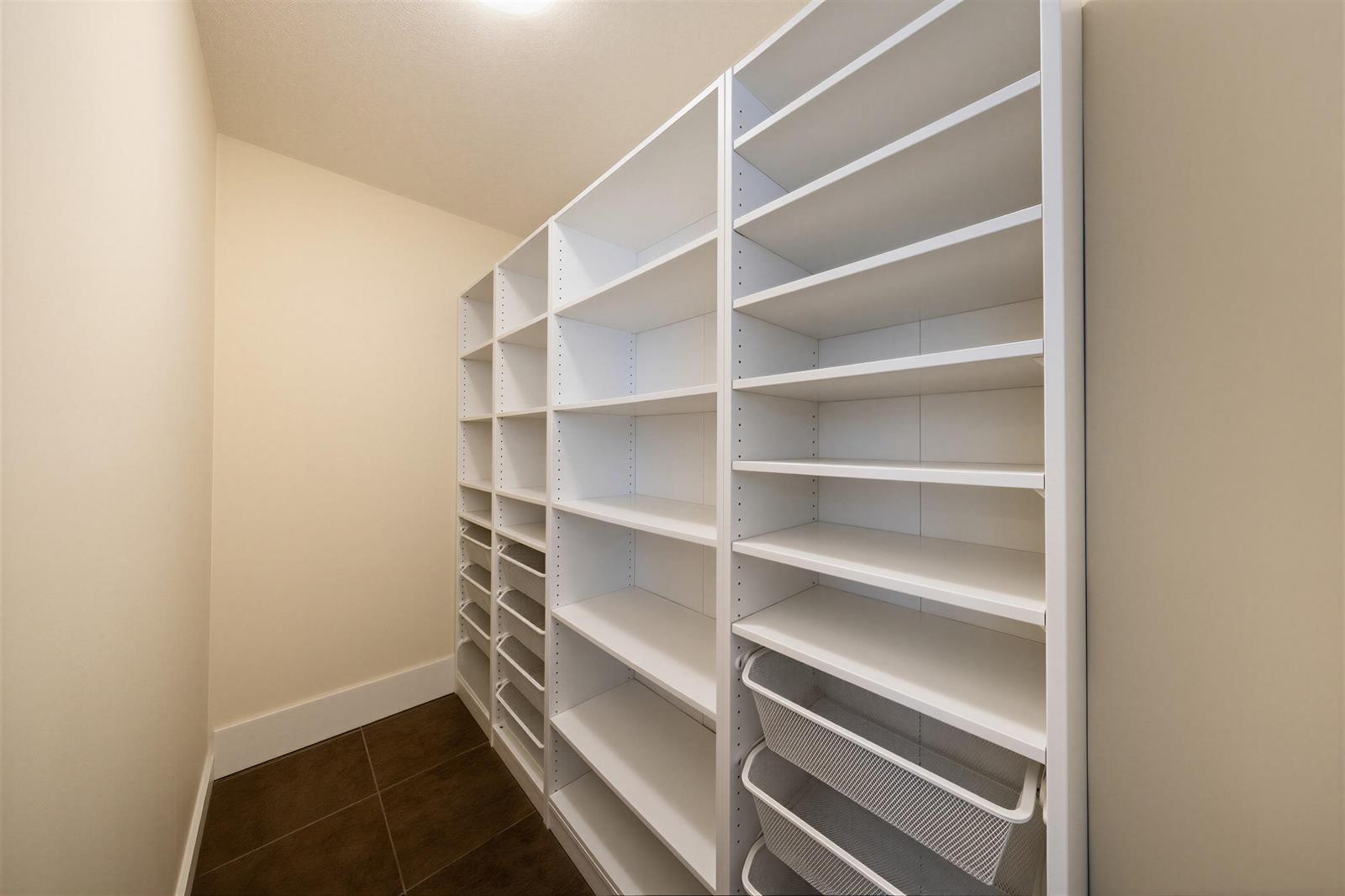 The storage room, white shelving floor to ceiling along both walls.