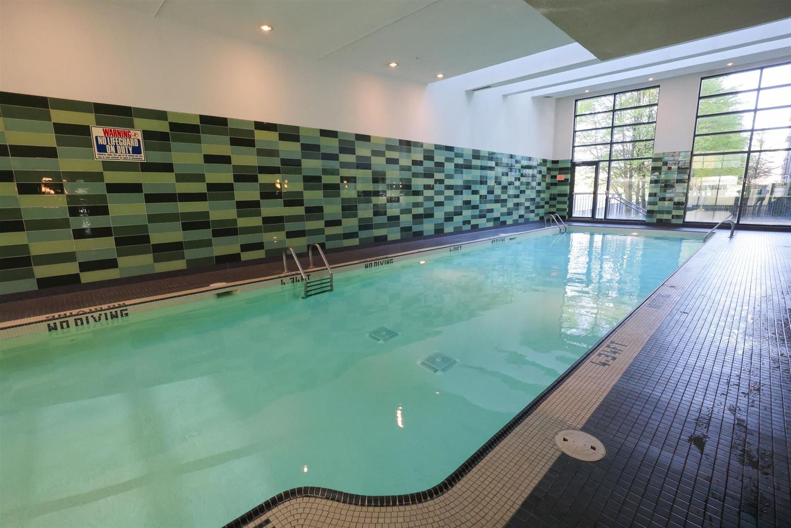 The indoor pool, tiled in green with the glass wall onto the garden at its end.