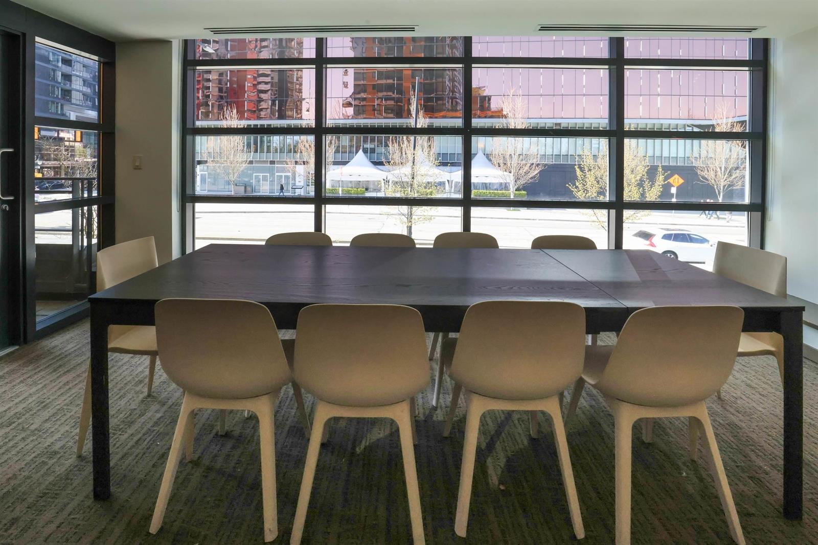 The meeting room, a long table and chairs under windows onto the street.
