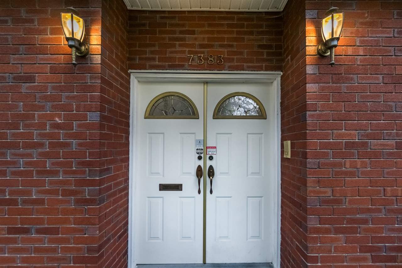 The entry, the double doors set into brick with a lantern on each side.