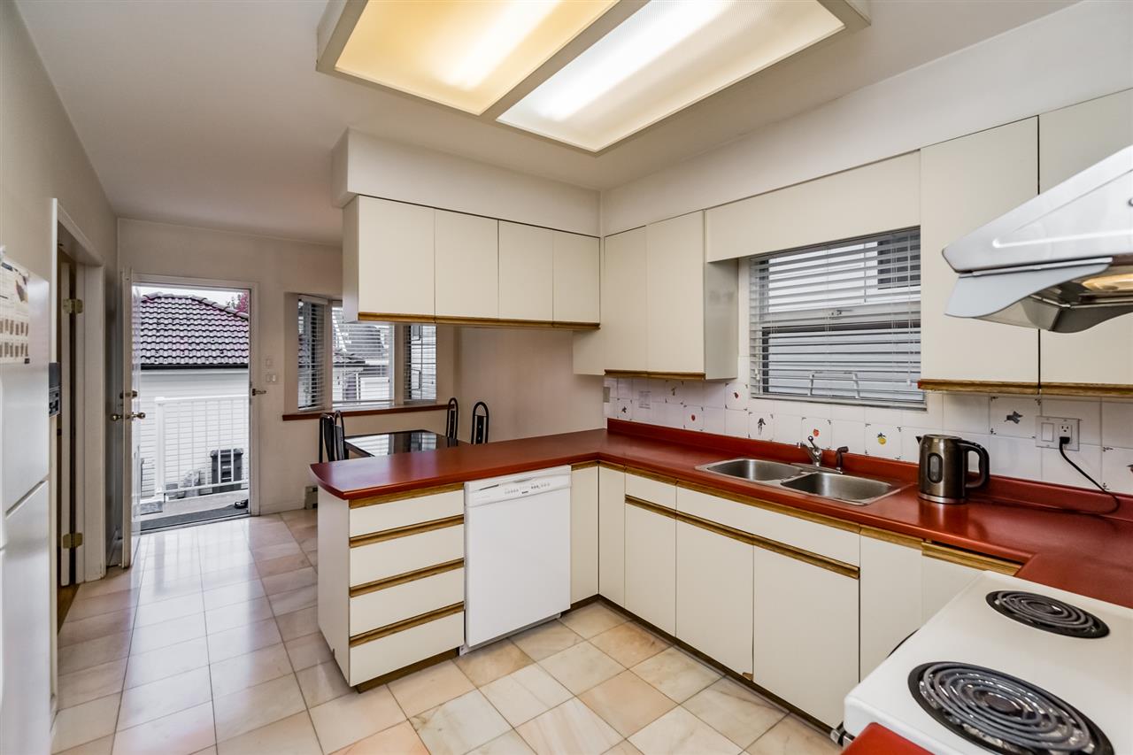 The kitchen from the doorway, the counter running to the corner and the yard through the window.