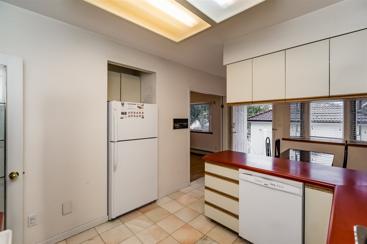 The kitchen from the far side, the fridge and the dishwasher with the counter turning the corner.