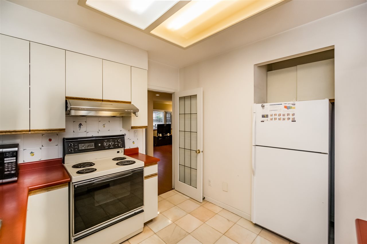 The kitchen along the range wall, the fridge beside the door through to the hall.