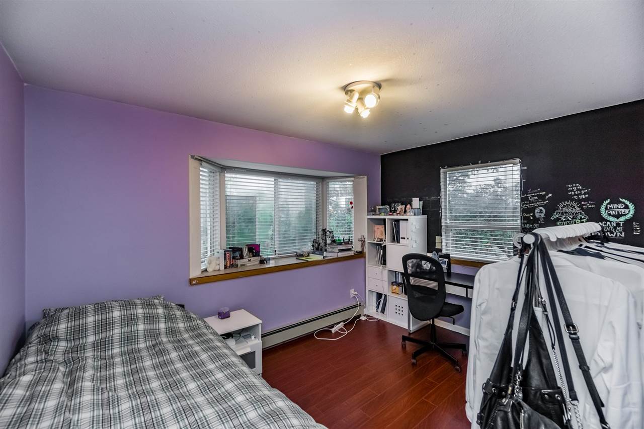 A bedroom with a purple wall, a desk and shelving under the window.