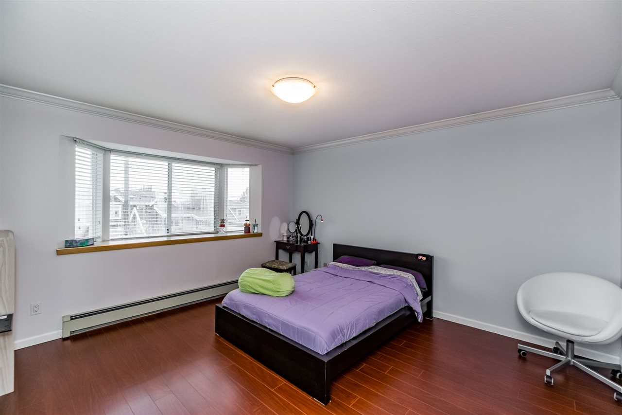 A bedroom, the bed under the window with a dressing table opposite.