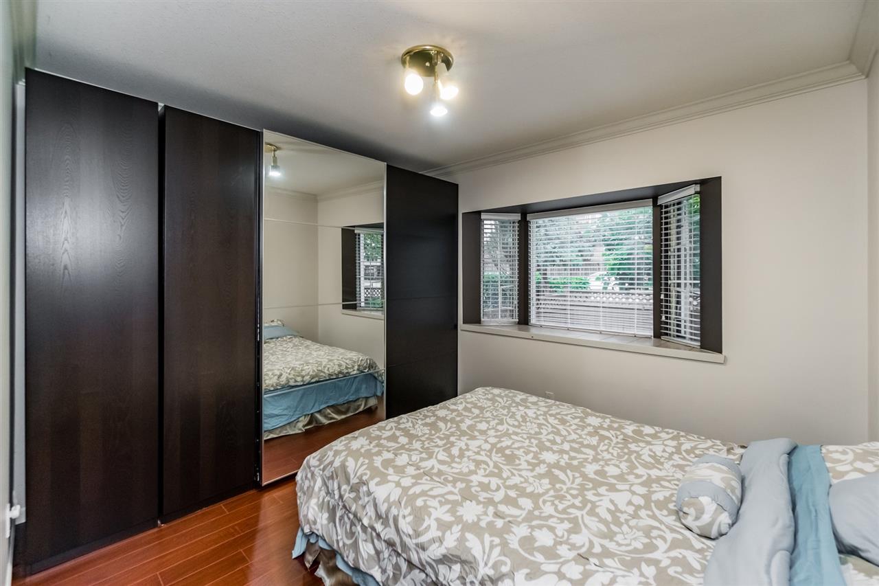 A bedroom with mirrored closet doors along one wall and the bed beneath the window.