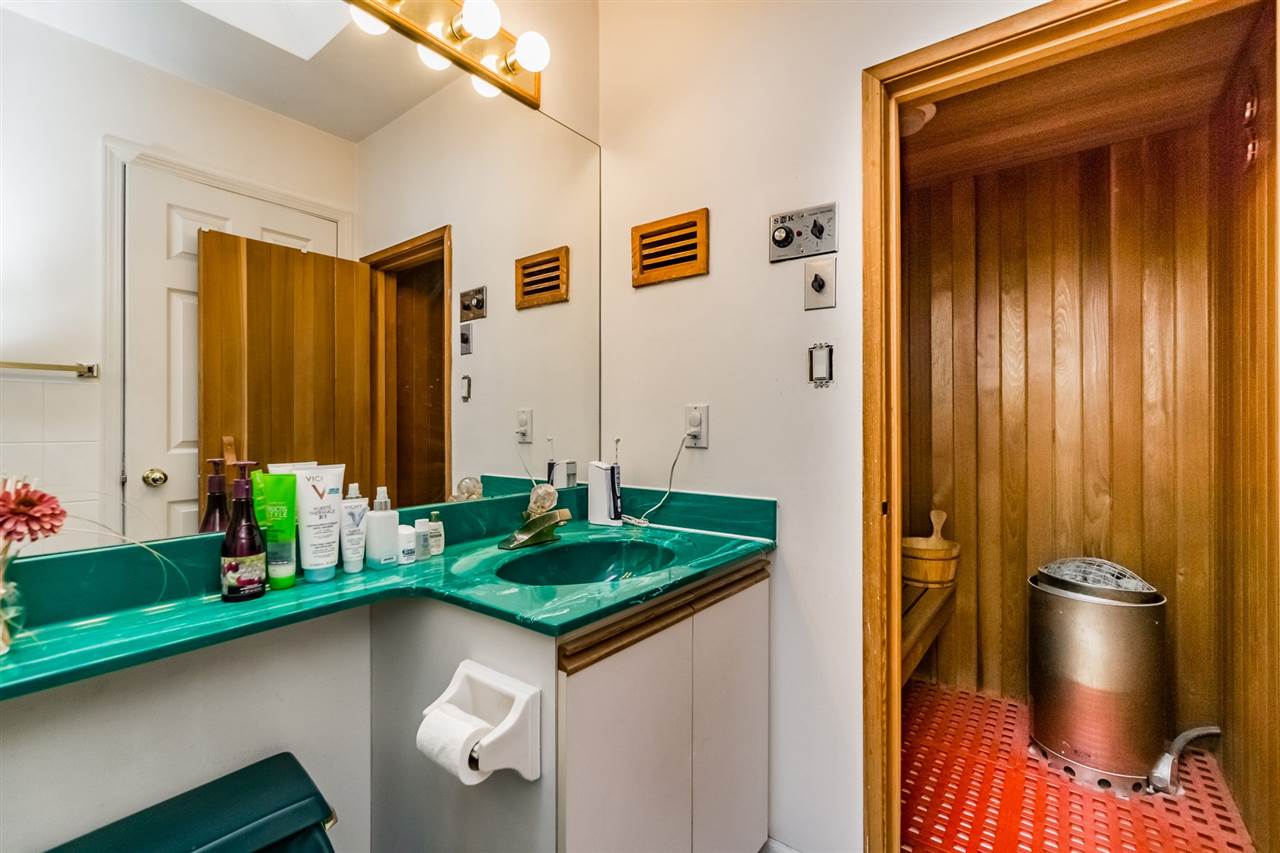The ensuite toward the sauna, the cedar door open at the end of the counter.