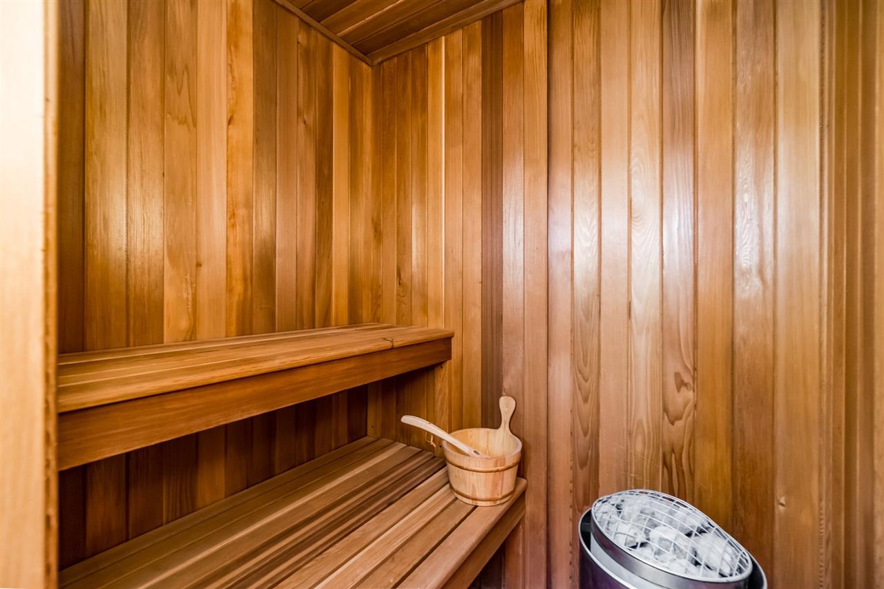 Inside the cedar sauna, the bench along the panelled wall with the bucket and ladle.