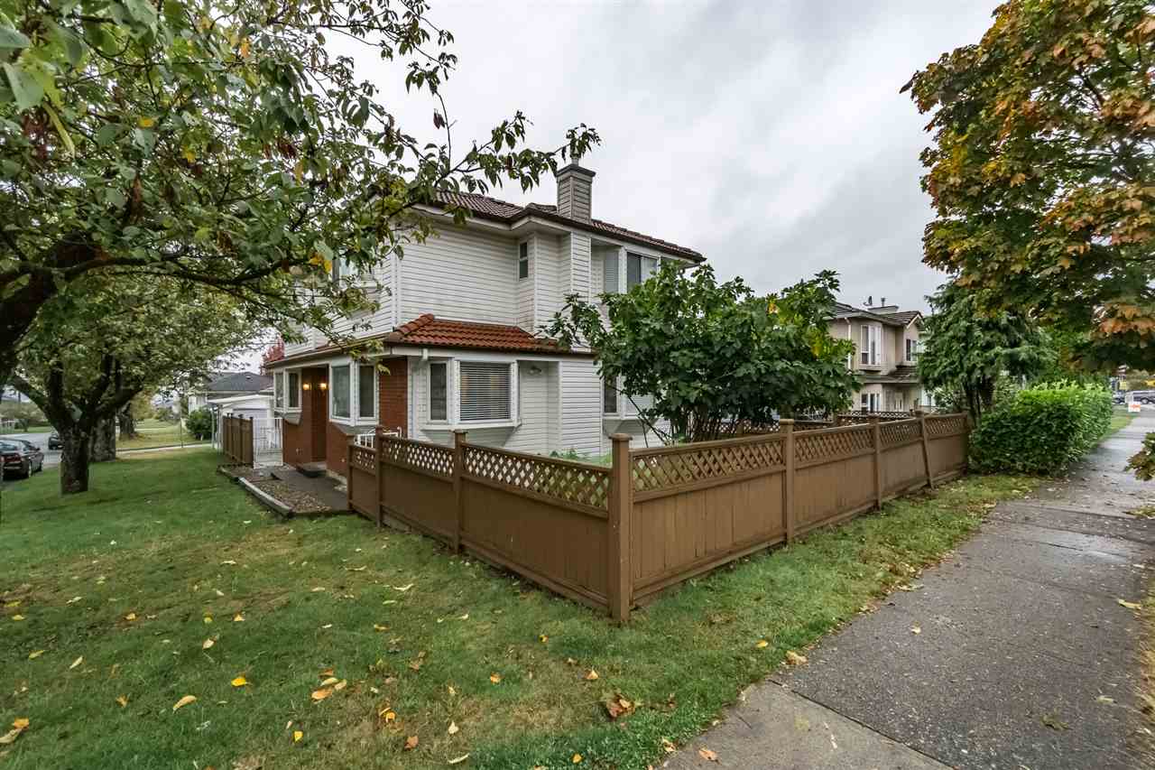 The house from along the street, the fenced corner lot with the trees turning over the lawn.