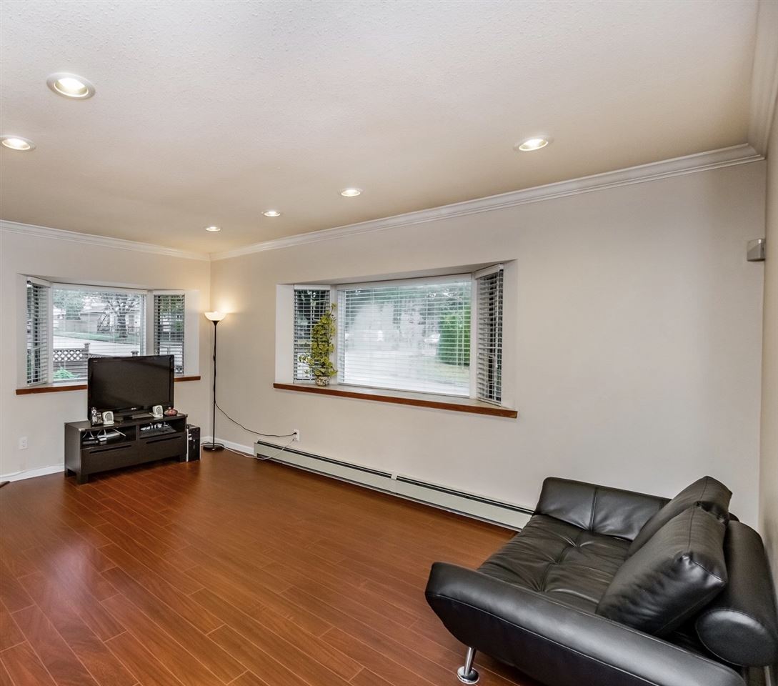 The living room from the corner, the seating turned toward the television with the windows behind.