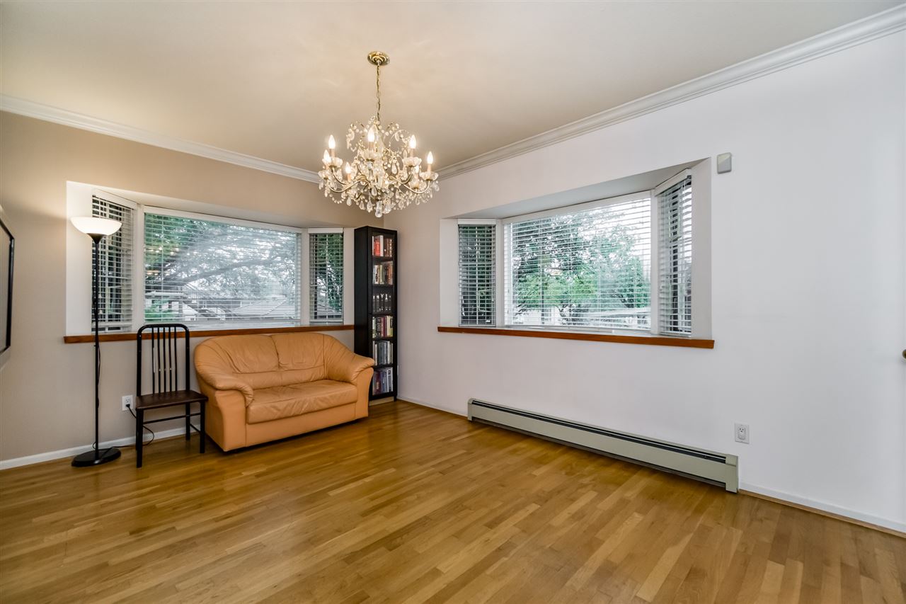 The living room from the other end, a sofa under the windows and hardwood running the length of the room.
