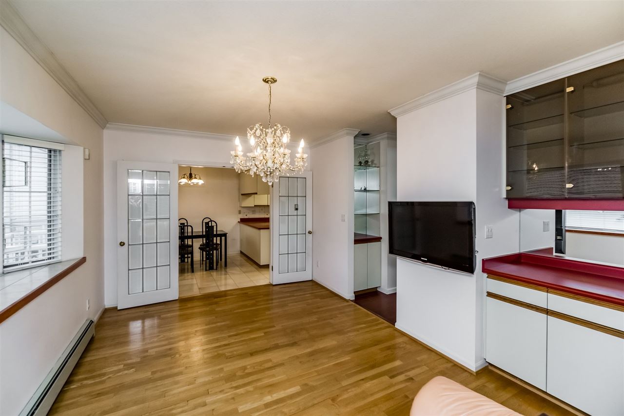 Through the living room to the dining room, French doors beyond and the chandelier above the table.