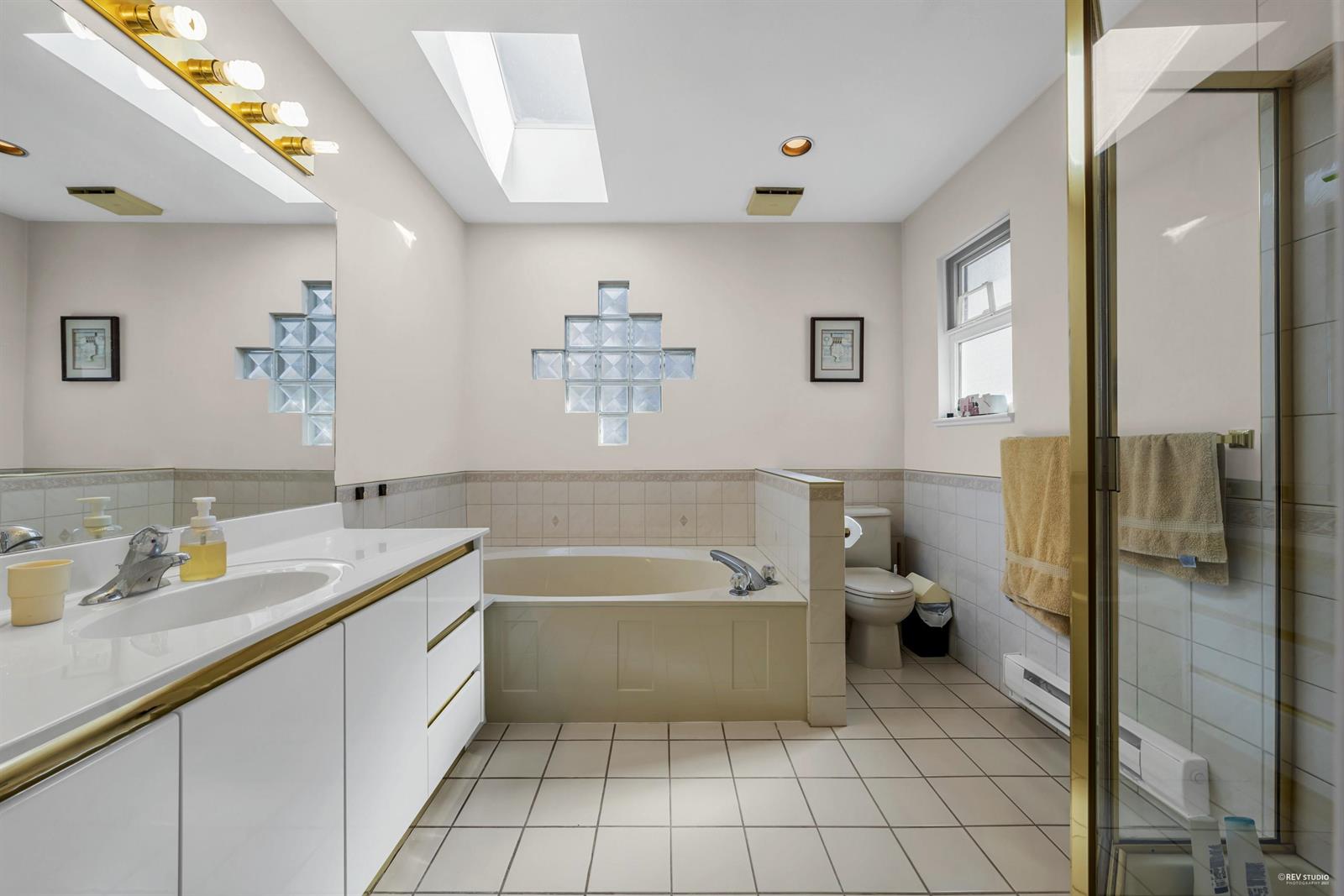 The bathroom, a soaking tub under a skylight beside a glazed shower.