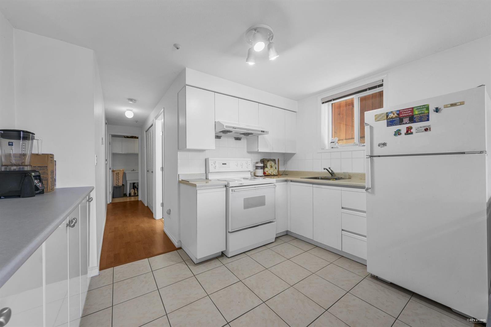 The kitchen in the lower suite, white cupboards with its own entrance beyond.