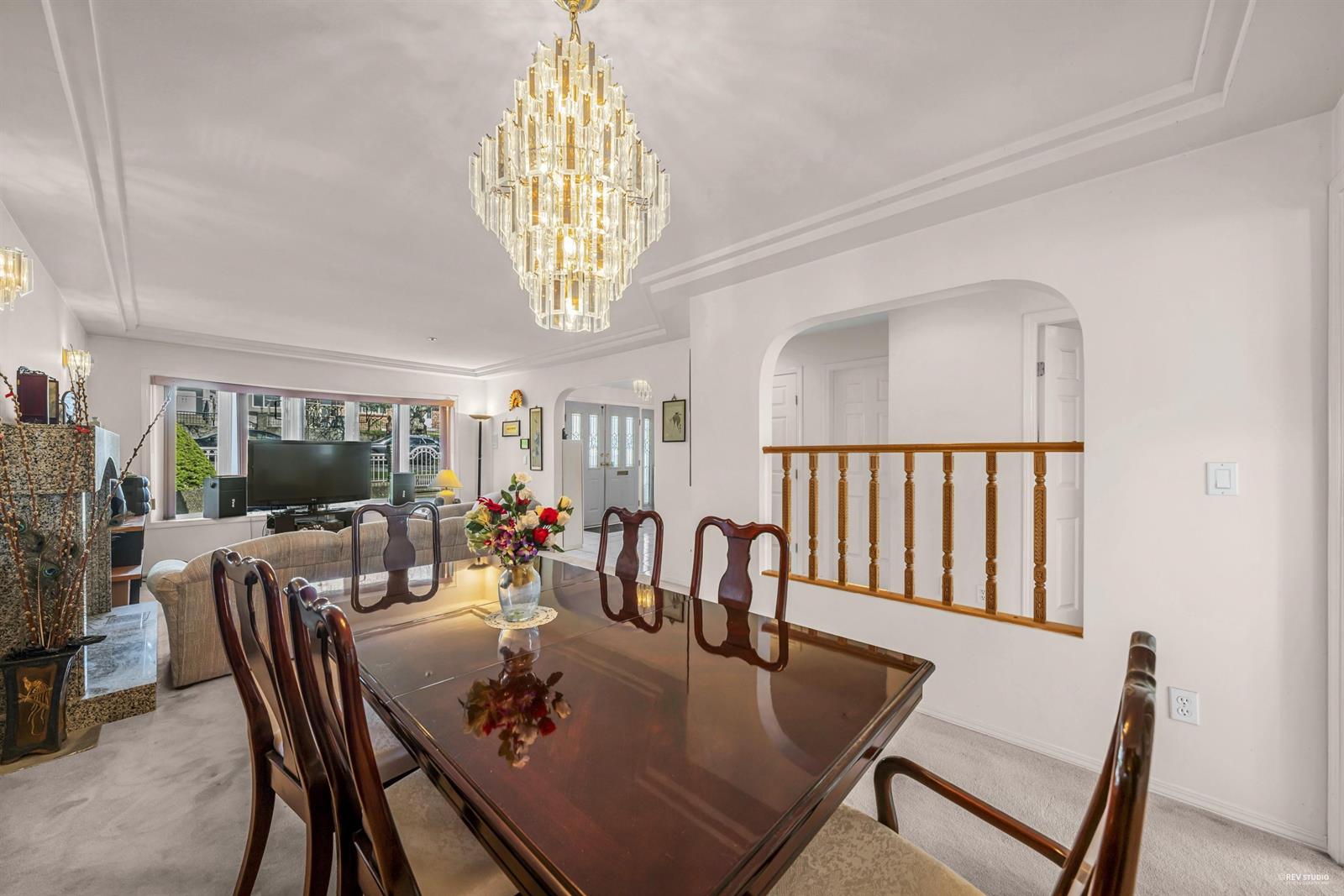 The dining room, a long table under a glass chandelier beside the stair rail.