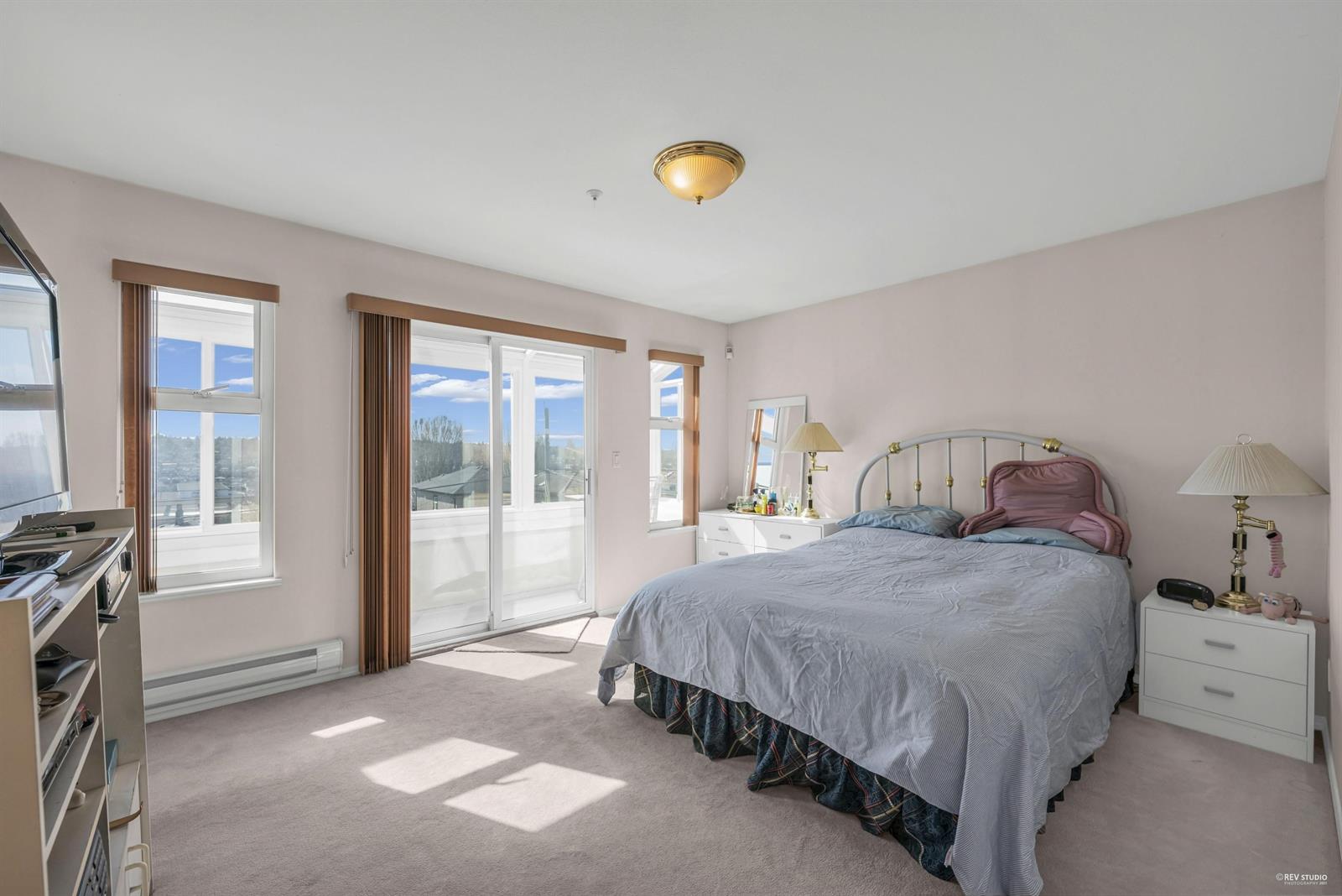 A bedroom with a sliding door out to a deck and the view beyond it.
