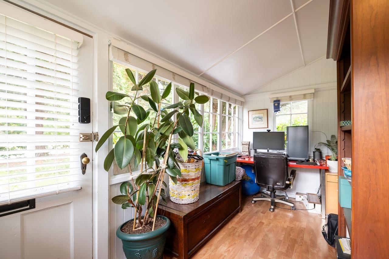 The office at the end of the house, a desk under a sloped ceiling with plants along the window.