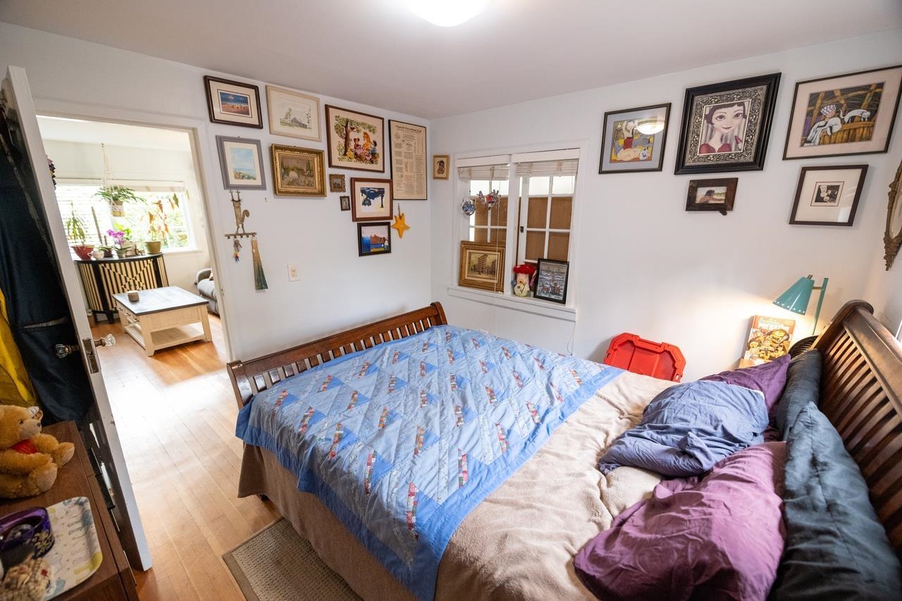 A bedroom with a bed against the wall and framed pictures hung above it.