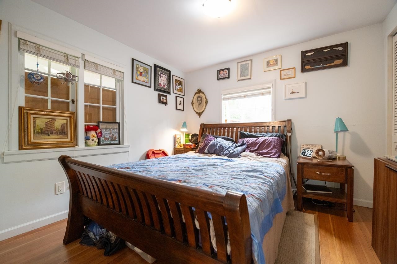The primary bedroom, a wooden sleigh bed between two windows.