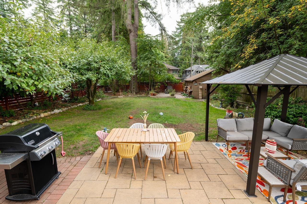 The patio from the garden, an outdoor table and sofa beneath the covered gazebo.