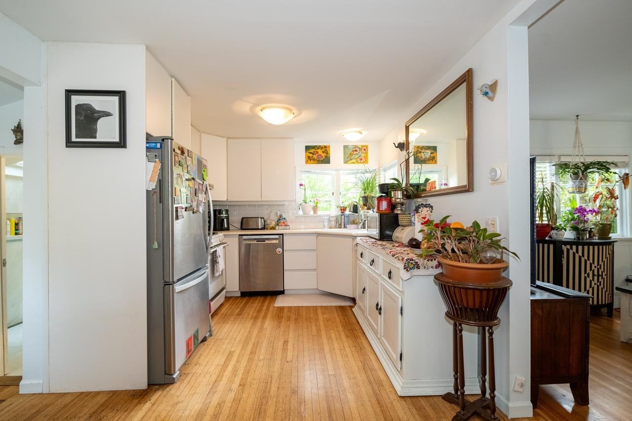 The kitchen fitted in white along two walls, a window over the counter and a mirror on the wall.