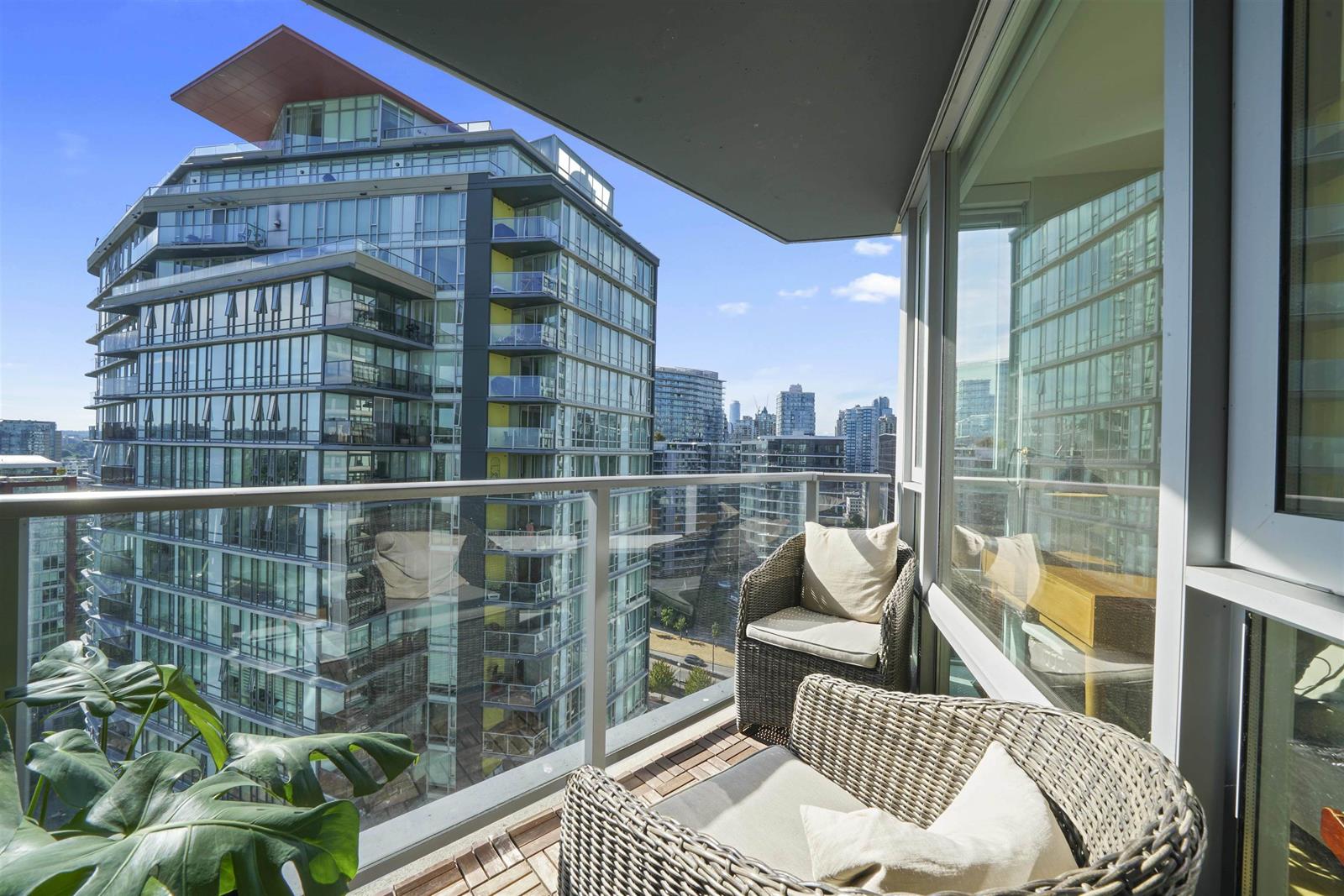 The balcony, a chair in the corner looking along the building's glass face towards the bridge.