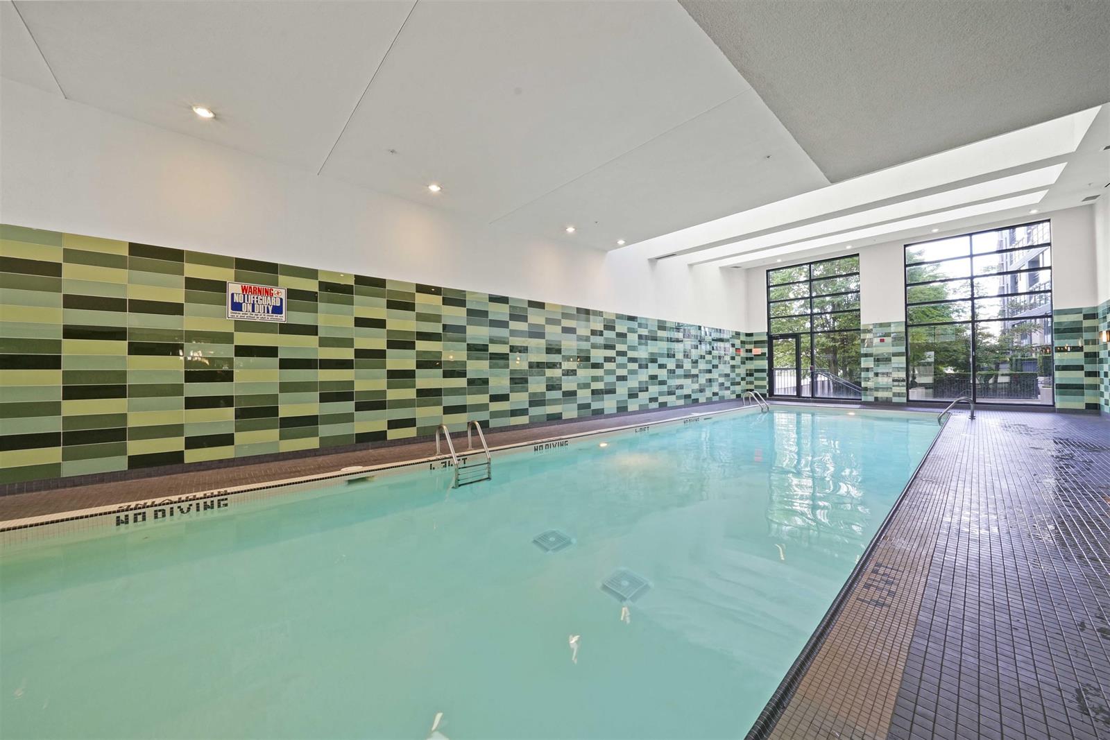 The building's indoor pool, tiled in green along one wall and glazed to the garden.