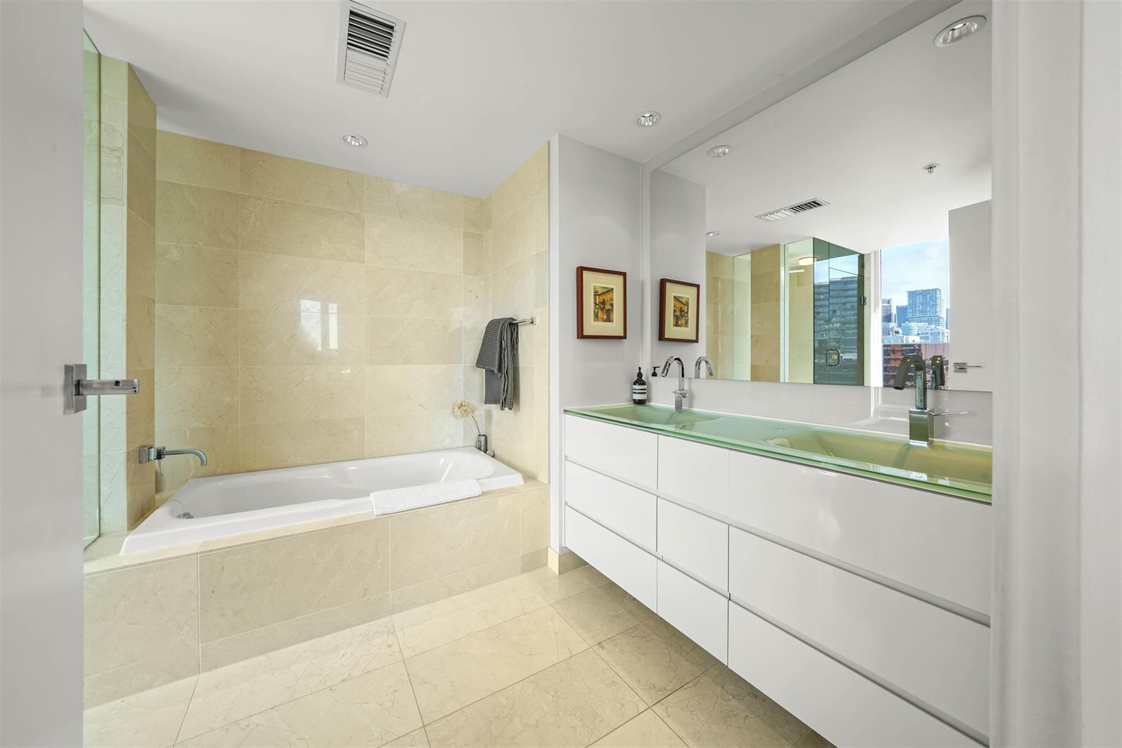 The ensuite, a bath set into stone beside a long vanity under a full-width mirror.