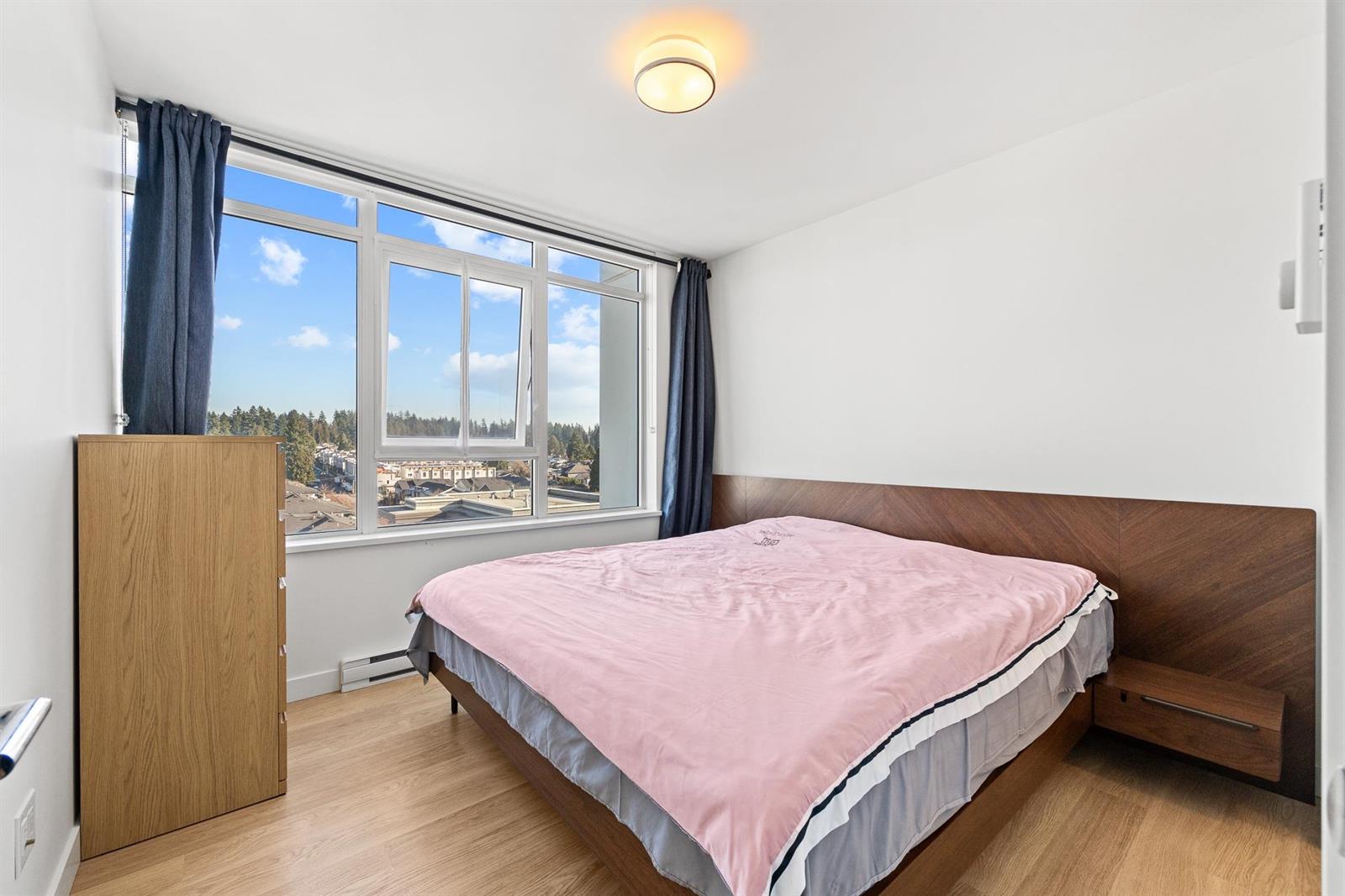 The primary bedroom, the bed under a window looking out over the rooftops.