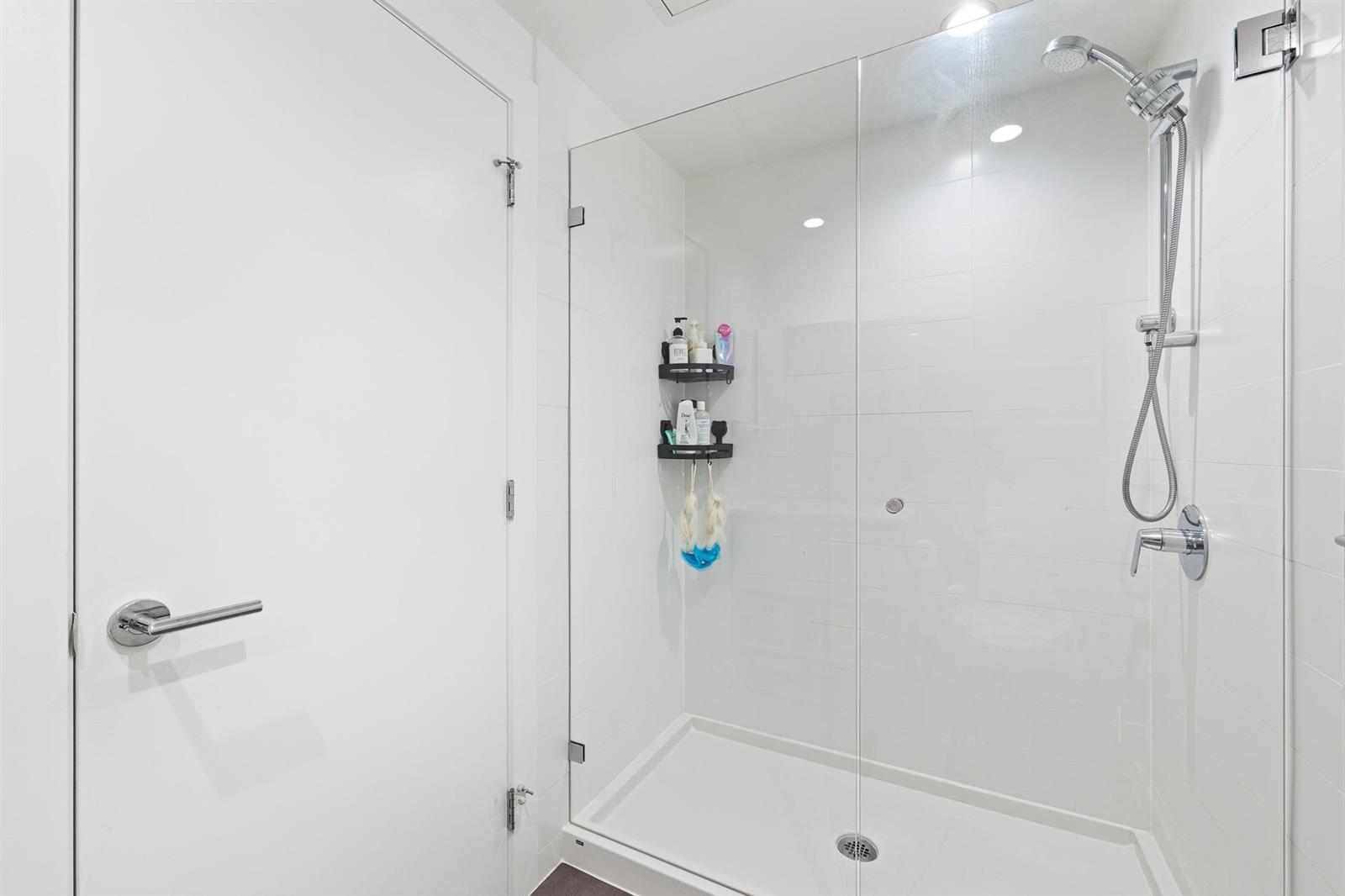 The ensuite shower behind a glass door.
