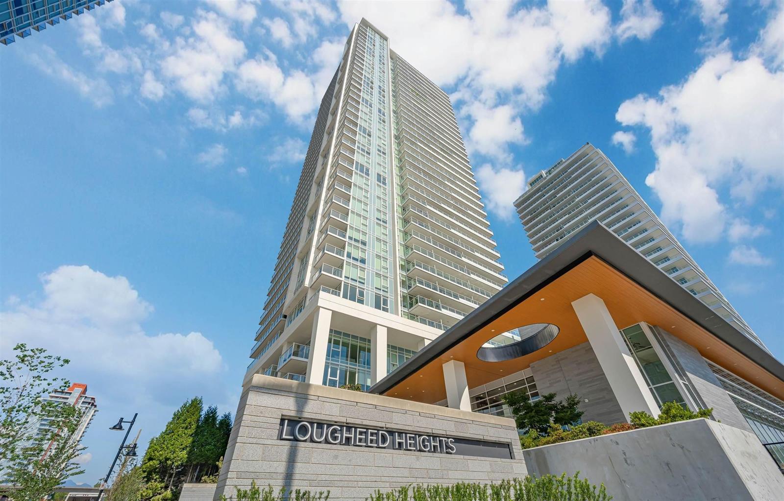 The tower from the forecourt, glass rising above the Lougheed Heights sign.