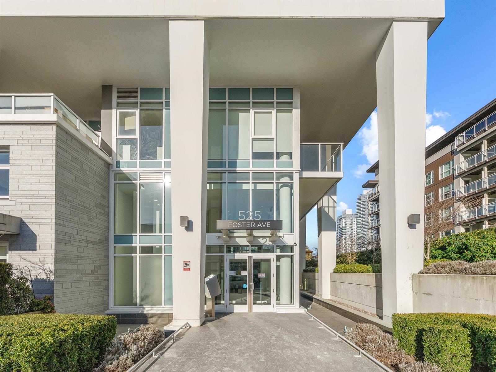 The entrance, glass doors set back between concrete columns.