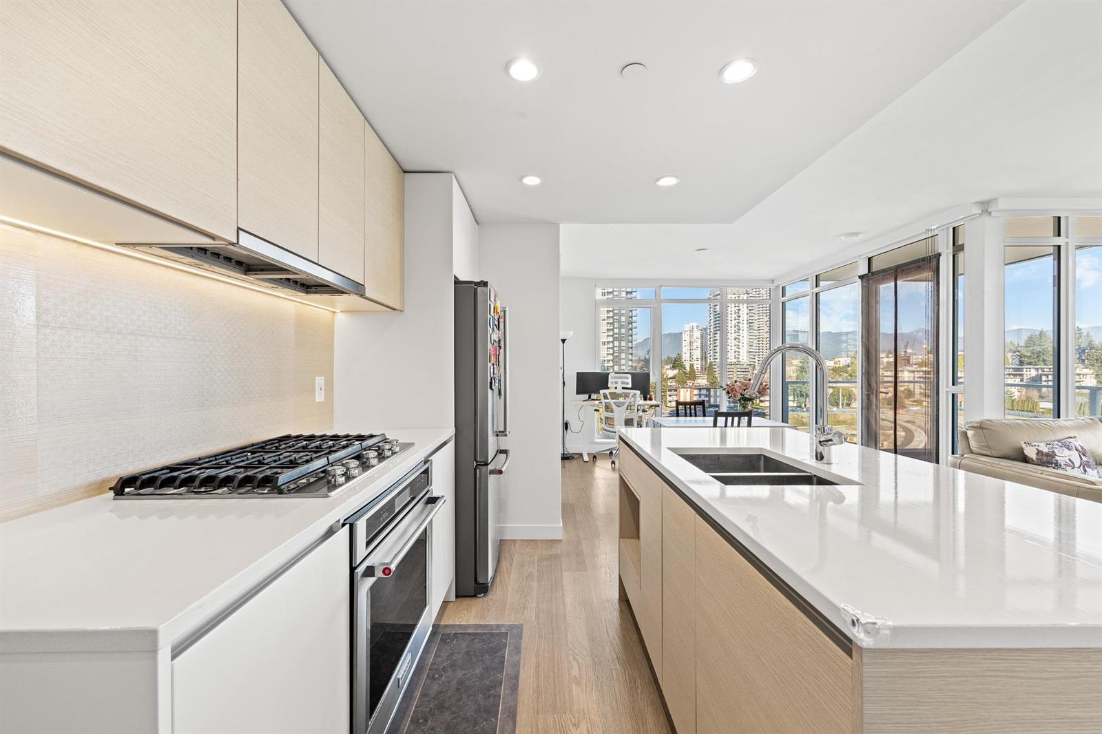 The kitchen, a gas cooktop under the hood with quartz counters either side.