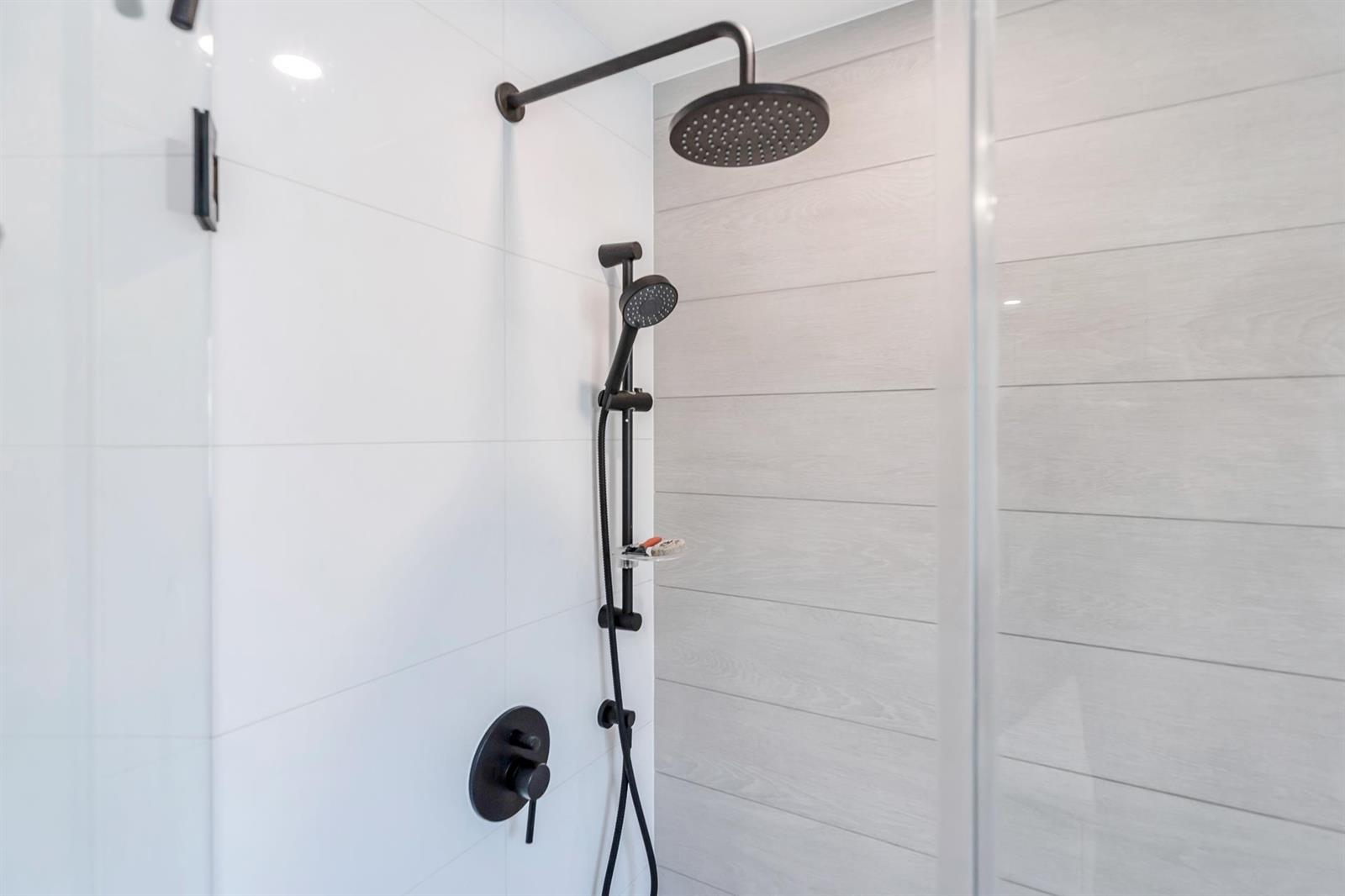 The shower, tiled floor to ceiling with a rainfall head.