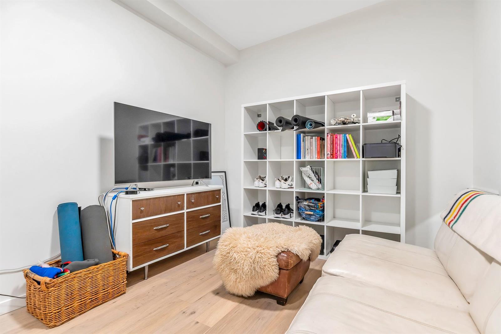 The lower room, shelving along one wall — a den, a gym or a media room.
